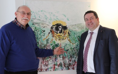 Bernd David, Vorsitzender der Inklusiven Künstlergemeinschaft Lippe, und Landrat Dr. Axel Lehmann vor dem Vereinssymbol von der „Hummel“.