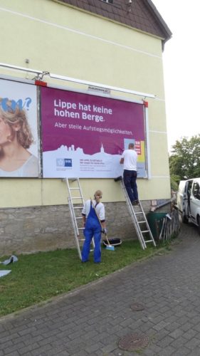 uch die IHK Lippe hat sich drei neue Sprüche ausgedacht. Hier wird gerade in Detmold ein Spruch zum Thema „Lippe hat keine hohen Berge. Aber steile Aufstiegsmöglichkeiten“ auf eine Großfläche geklebt.