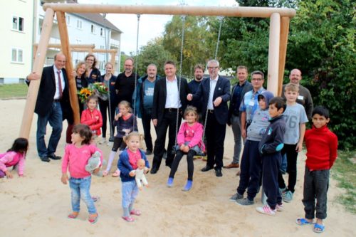 Auf dem Foto sehen die Vertreterinnen und Vertreter des christlichen Aktionsbündnisses „CONTACT!DETMOLD“ , des Meisterchores „nota bene“, der Bezirksregierung Detmold und der Stadt Detmold mit Bürgermeister Rainer Heller (hinten links), Tabea Beer (ASB) und geflüchteten Kindern auf dem neuen Spielplatz der ZUE Adenauerstraße